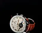 Silver wristwatch with a brown leather strap on a black background