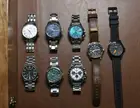 Eight wristwatches laid out in two rows on brown leather