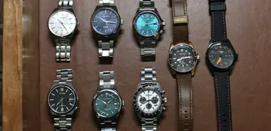 Eight wristwatches laid out in two rows on brown leather