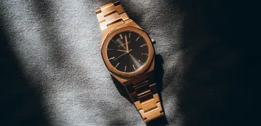 Gold wristwatch with a black dial on grey fabric